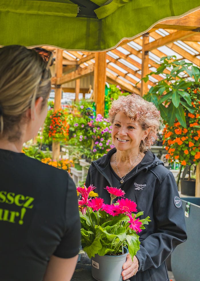 Conseillère avec une cliente tenant un pot de fleur rose