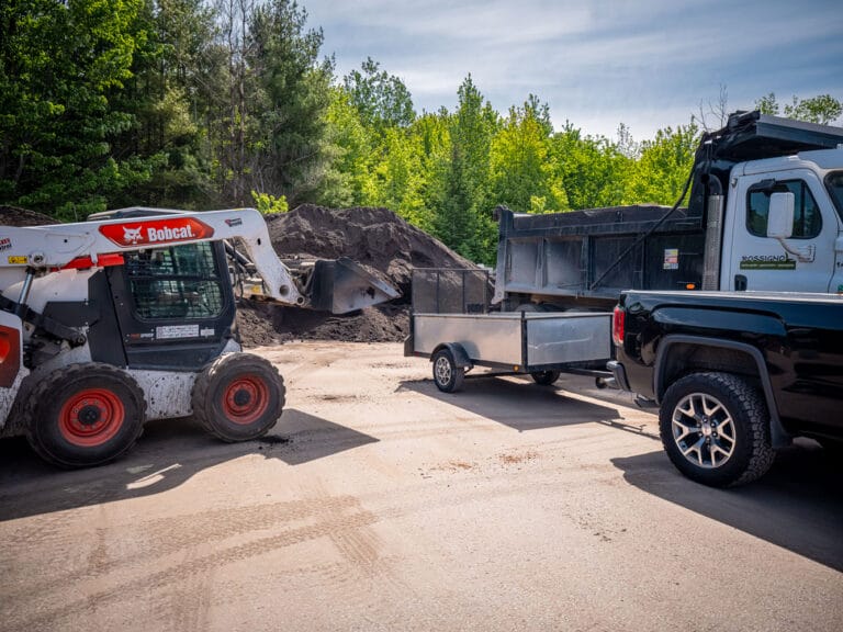 Petite pelle mécanique qui met de la terre dans une remorque d'un client à Gatineau